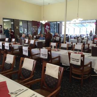 A spacious dining area with neatly arranged tables and chairs, each adorned with white tablecloths.