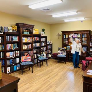 A cozy bookstore with neatly arranged bookshelves and a wooden floor, featuring a reading area and a person browsing through the selections.