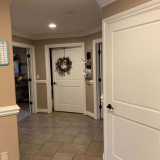 A cozy home hallway with beige walls and multiple doors, featuring a wreath on the central door.