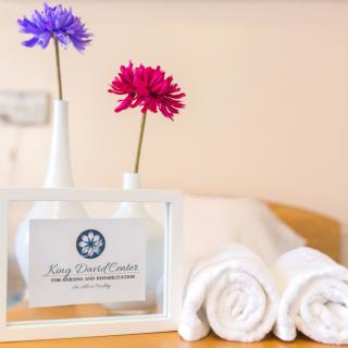 Rolled white towels with flowers in vases, creating a spa-like atmosphere.