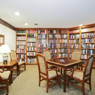A cozy library with wooden bookshelves and a seating area for reading.