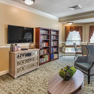 A cozy living room with a television, bookshelf, and comfortable seating arrangement.