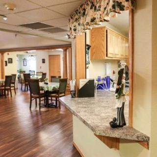 A cozy dining room with wooden floors and elegantly arranged tables and chairs.