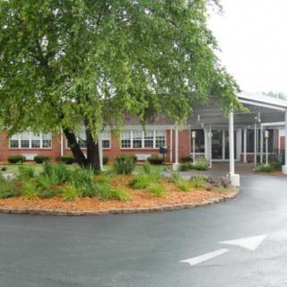 A building entrance with landscaped greenery and a roundabout driveway.