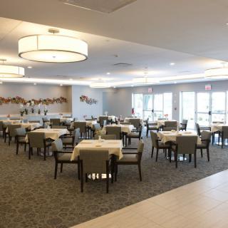 A spacious and modern dining room with neatly arranged tables and chairs, illuminated by stylish ceiling lights.