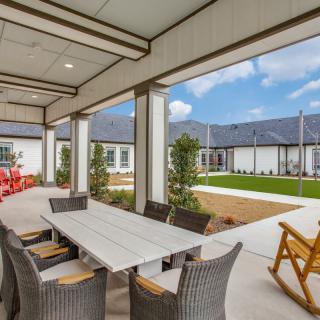 A spacious outdoor patio with a dining table and chairs overlooking a well-maintained garden.