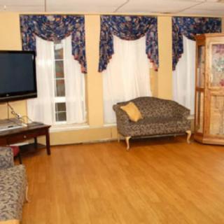 A cozy living room with a mounted television, sofas, and decorative curtains.