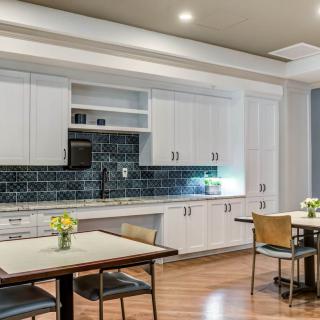 A modern kitchen and dining area with white cabinets, a black backsplash, and wood flooring.