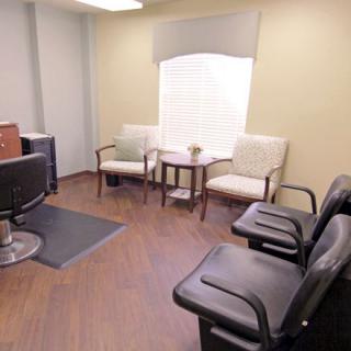A waiting room with comfortable chairs and a small table, featuring a welcoming atmosphere.