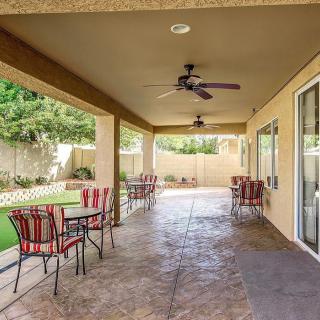 A covered patio with outdoor seating and ceiling fans overlooking a garden.