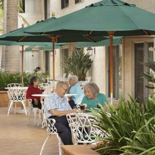 People enjoying a conversation at an outdoor cafe with green umbrellas.