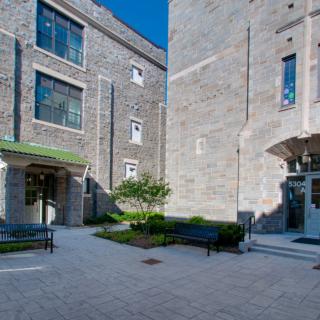 A courtyard surrounded by brick buildings with benches and greenery.