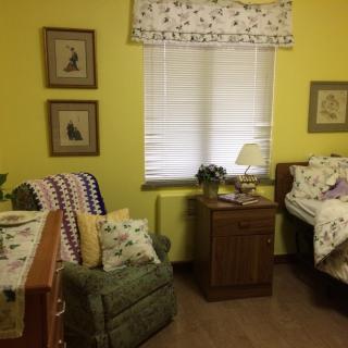 A cozy bedroom with yellow walls, featuring an armchair, bed, and nightstand.