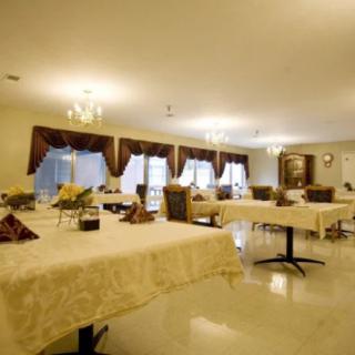 A well-lit dining room with tables covered in white tablecloths and elegant chandeliers hanging from the ceiling.