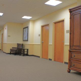 A quiet office hallway with several doors and a wooden cabinet.