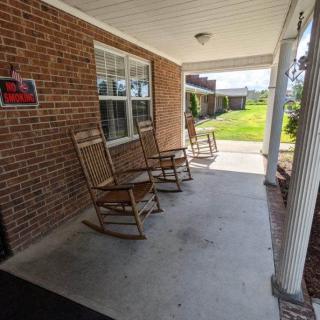 A cozy front porch with rocking chairs against a brick wall.