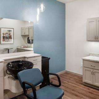 A hair salon interior with a styling chair, mirror, and sink against a blue accent wall.