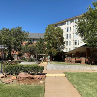 A sunny day view of a building surrounded by trees and green lawns.