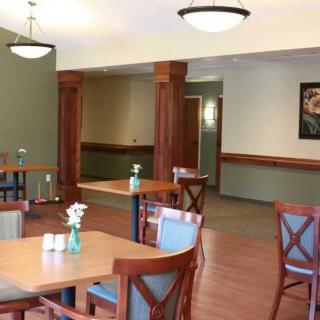 A cozy dining area featuring wooden tables and chairs, complemented by simple decor and overhead lighting.