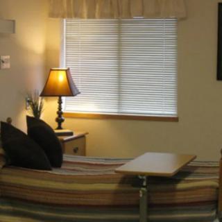 A cozy bedroom with a lamp, window blinds, and comfortable furnishings.