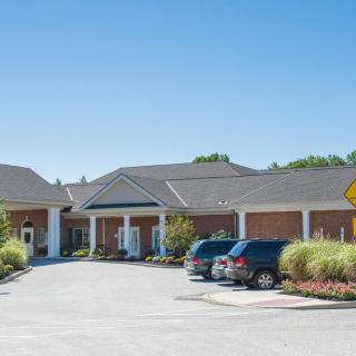 A view of a building with a parking lot and several cars under a clear blue sky.