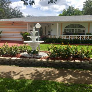 A suburban house with a well-maintained lawn and a decorative fountain in the front yard.