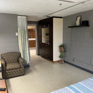 A cozy room featuring a patterned chair, shelving unit, and soft lighting.
