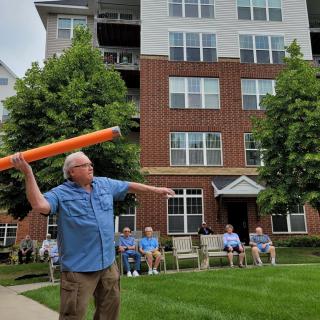 A group of seniors enjoying an outdoor activity in front of a multi-story building.