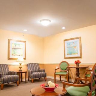A cozy living room with striped chairs, a round table, and framed artwork on the walls.