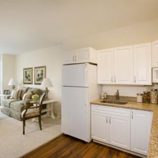 An open-plan apartment featuring a kitchen with white cabinets and a cozy living area.