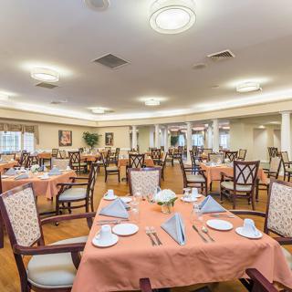 An elegantly set dining room with multiple tables and chairs, prepared for guests.