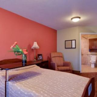 A cozy bedroom with a bed, comfortable chair, and warm lighting.
