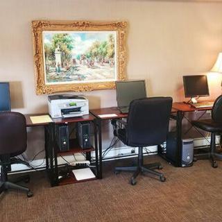 An office space with several workstations equipped with computers, a printer, and a decorative painting on the wall.