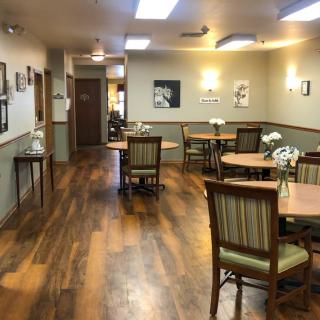 A cozy dining area with wooden floors and neatly arranged tables and chairs.