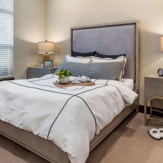 A cozy bedroom featuring a neatly made bed with pillows and modern bedside lamps.