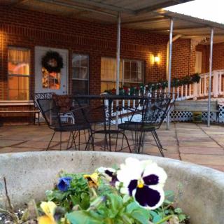 A cozy patio with a table and chairs, adorned with pansy flowers and evening lighting.