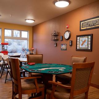 A cozy game room featuring a poker table surrounded by chairs, decorated with wall art and warm lighting.