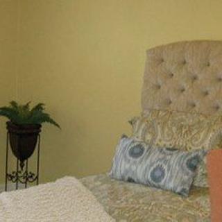 A cozy bedroom with a tufted headboard, patterned pillows, and a potted plant.