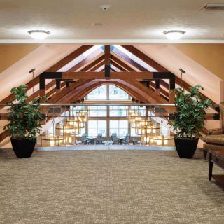 A spacious atrium with large glass windows, wooden beams, and a cozy seating area.