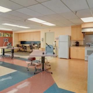 A modern office kitchen area with desks and seating arrangements.