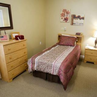 A neatly arranged bedroom with a single bed and wooden furniture.