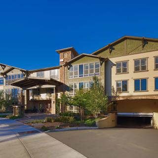 A modern residential building with well-maintained landscaping and a clear blue sky.