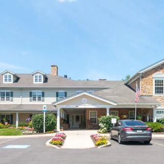 A two-story building with a welcoming entrance and parked car in front, under a clear blue sky.