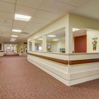 An empty office hallway with a reception desk and ceiling lights.