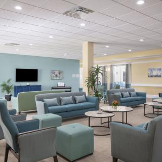 A spacious and modern lounge area with comfortable seating, a television, and decorative plants.