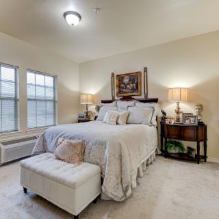 A cozy bedroom with a neatly made bed, nightstands, and soft lighting.