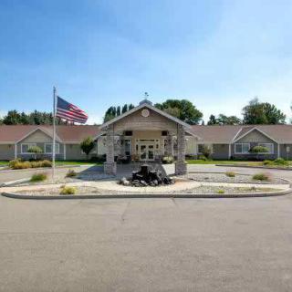 A residential building with an American flag at the entrance, surrounded by a driveway and landscaped area.