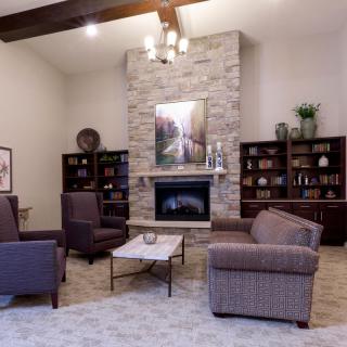 A cozy living room featuring a fireplace, armchairs, and bookshelves with modern decor accents.
