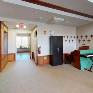 An interior view showcasing a hallway with a kitchenette and a piano.
