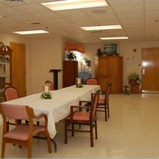 A well-lit dining room with a long table and several chairs, decorated with small centerpieces.